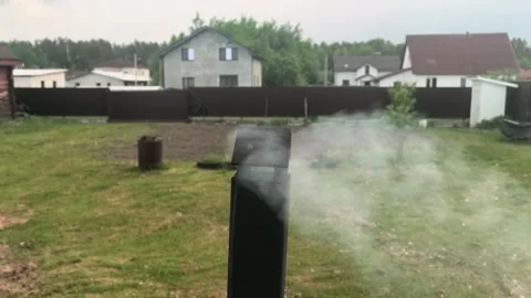Smoke rises from the chimney in a backyard while houses stand in the background  Stock Footage 335406816