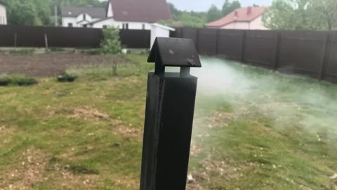 Smoke rises from the chimney in a backyard while houses stand in the background  Stock Footage 335406944