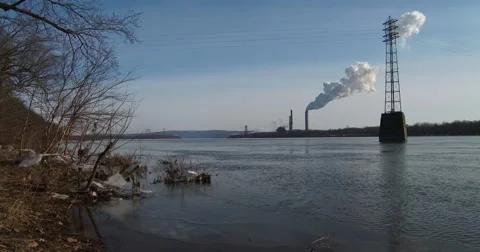 Smoke rises from a distant power plant along a river. 動画素材 41856949