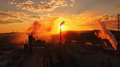 Smoke rises from factories during sunset in an industrial zone located in the Stock Footage 340879668