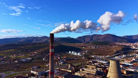 Smoke rises from a factory stack in a mountainous region during daylight hours 库存影片 335407569