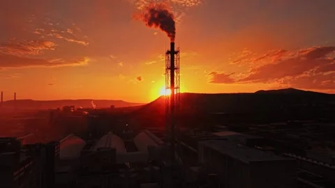 Smoke rises from a factory as the sun sets over the landscape Stock Footage 339651208