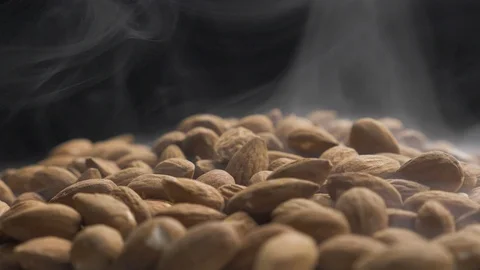 Smoke rises through almonds which spin on a black background Stock Footage 118470054