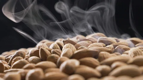Smoke rises through almonds which spin on a black background Stock Footage 118470093