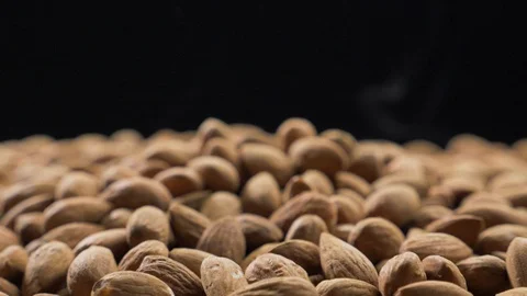 Smoke rises through almonds which spin on a black background Stock Footage 118470122