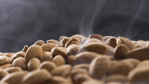 Smoke rises through almonds which spin on a black background Stock Footage 120083323