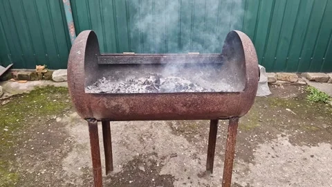 Smoke Rising from Rusty Diy Metal Barbecue Grill in Front of Green Fence Stock-Footage 339003733