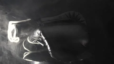 Smoke rising in slow motion around boxing gloves close up isolated on black Stock Footage 205042906
