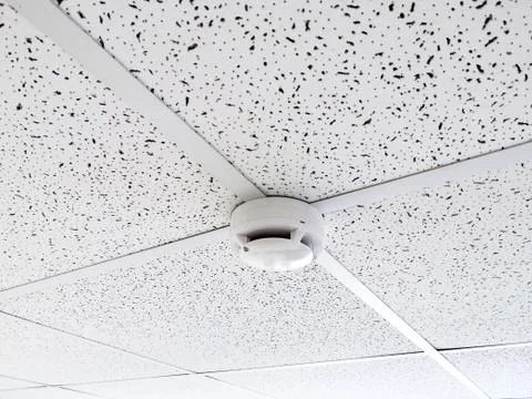 Smoke sensor on the ceiling in the office room. Fire alarm element. Workspace Stock Photos