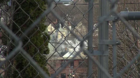 Smoke stack and church looking through chain link fence Stock Footage 304366175