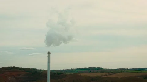 Smoke stack with dense grey fumes rising above industrial factory complex. Large 库存影片 334663113