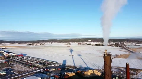 Smoke stack emits grey white cloud of fumes, long shadow cast onto snow Vídeos de archivo 257391686