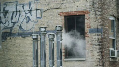 Smoke stack releasing a smoke against brick wall Stock Footage 100049433