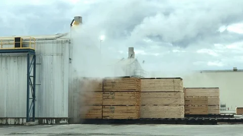 Smoke stacks at lumbar yard with stacks of wood Stockbeeldmateriaal 122585762