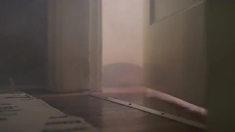 Smoke starts flowing through a crack in the door of a room Stockbeeldmateriaal 134299783