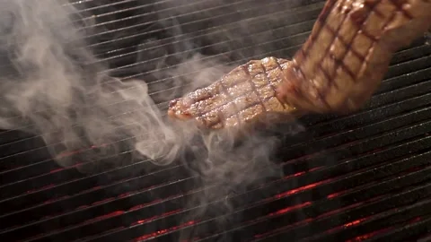 The smoke of two steaks on the grill and the roast of the steaks by the cook Stock Footage 143203353