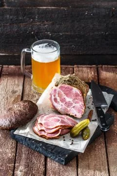 Smoked ham with rye bread, pickles and beer, rustic style Stock Photos