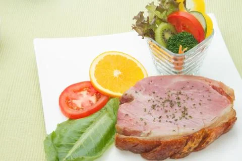 Smoked ham stack with fruit and vegetable salad on the white plate Stock Photos