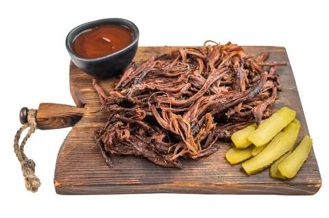 Smoked pulled beef brisket served on wooden board with pickles and sauce, r.. Stock Photos