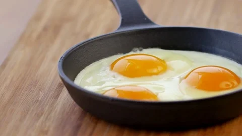 Smokes on eggs, freshly cooked,Fried eggs in pan,Black cast iron pan,wooden on t 스톡 동영상 85330940