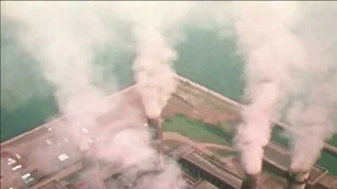 Smokestacks belch toxins at polluting factories and cargo ships are shown as Stock Footage
