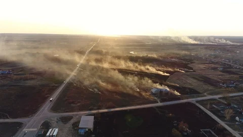 Smoking Burning Grass on the Side of the Road next to a Plowed Field. Firefighte Stock Footage 128941198