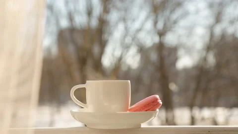 A smoking Cup of hot tea or coffee with macaroni cookies at window side abstract Stock Footage 87746225