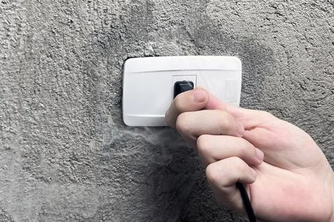 A smoking electrical outlet, a hand pulling the plug out of a burning outlet Stock Photos