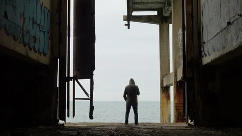 Smoking man in front of the sea inside a dark building Stock Footage 94344174