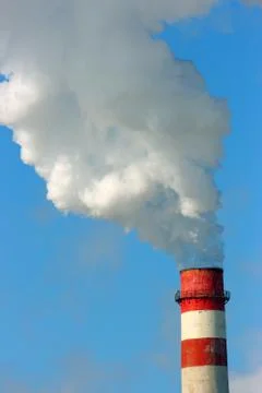 Smoking stack of the thermal power station against a blue sky Stock Photos