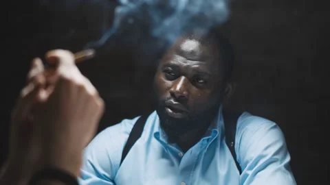 Smoking suspect with handcuffs being interviewed in interrogation room by police Stock Footage 142814170