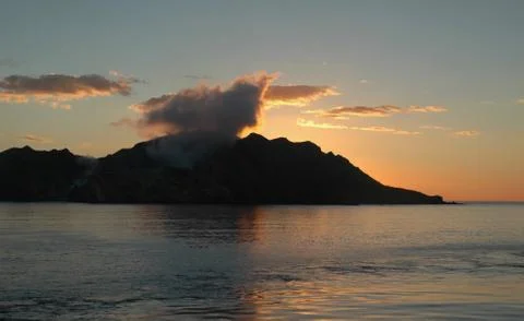 Smoking volcano at sunset. Stock Photos