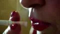 Smoking woman with red nails and red lips exhales through the nose and mouth HD Footage
