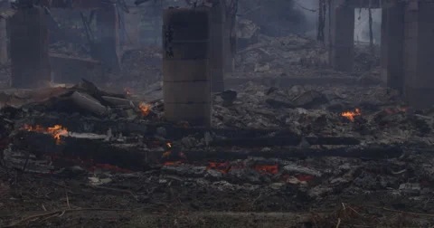 Smoldering charred rubble around the foundation supports of a burned house Stock Footage 59515425