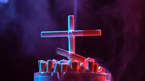 Smoldering cross of cigarettes. 库存影片 75656033