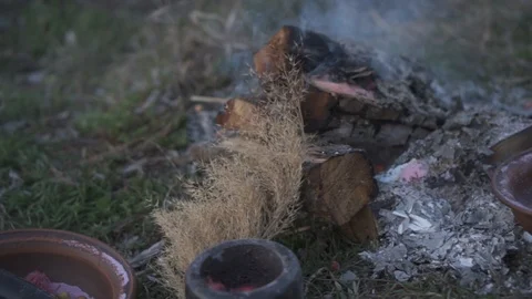 Smoldering steaming log and ash on the ground near clay bowls Stock Footage 110693728