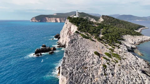 Smooth aerial drone orbit around a white lighthouse located on a rocky Stock Footage 336901642