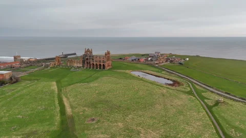 Smooth aerial drone pull back from the historic ruins of Whitby Abbey Stock Footage 346839024