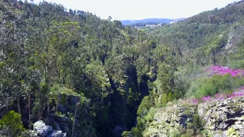 Smooth aerial exploring of a small cottage near a waterfall in a rocky canyon Stock Footage