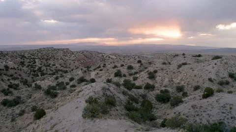 Smooth aerial over hills sunset peeking through rain clouds over New Mexico Stock Footage
