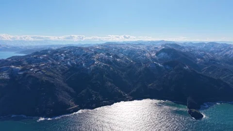 Smooth Aerial Pullback From Snowy Mountains Over Blue Sea Stock Footage 342848974
