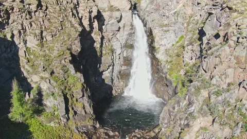 A smooth approach to the waterfall in the bowl between the rocks on a sunny day. Stockbeeldmateriaal 264093043