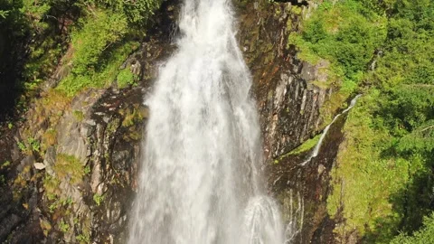A smooth ascent in front of a large waterfall between green trees and rocks on a Stock Footage 269300020