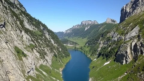 Smooth backwards Drone shot of alpine valley with lake during daytime Stock Footage 122220208