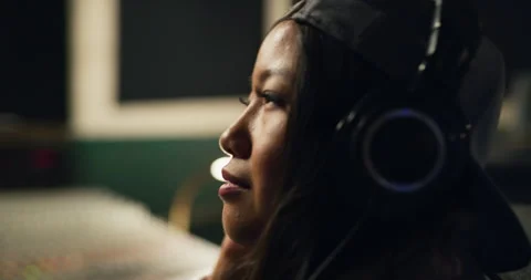 Smooth beats and a smooth shot. A female DJ and sound designer listening to her Stock Footage 199457966