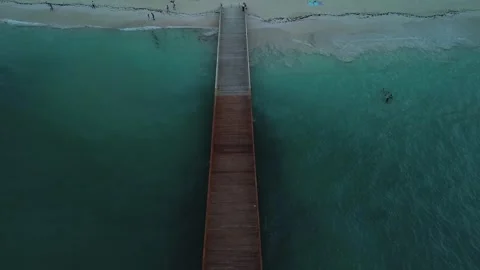 Smooth camera ascent captures perspective of pier, tourist beach, and hotel Video stock 273532682