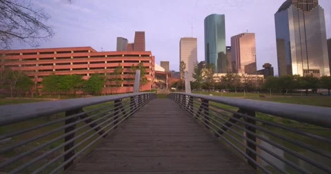 Smooth camera motion gliding over a charming pedestrian bridge with downtow.. Vidéo 334774897