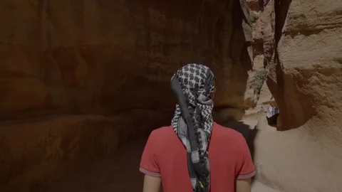 Smooth Camera movement with a man in the middle of canyon rock in Petra Stock Footage 102779129
