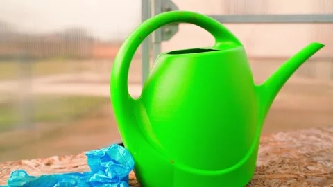 Smooth camera parallax around green garden watering can in greenhouse, close-up Stock Footage 307269791