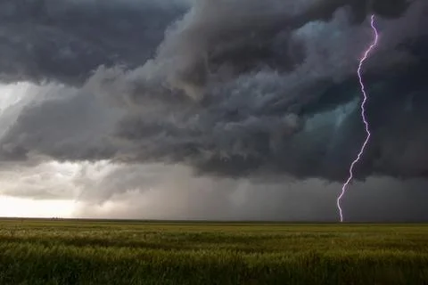 A smooth channel lightning bolt arcs to the ground through the turbulent updraft Stock Photos